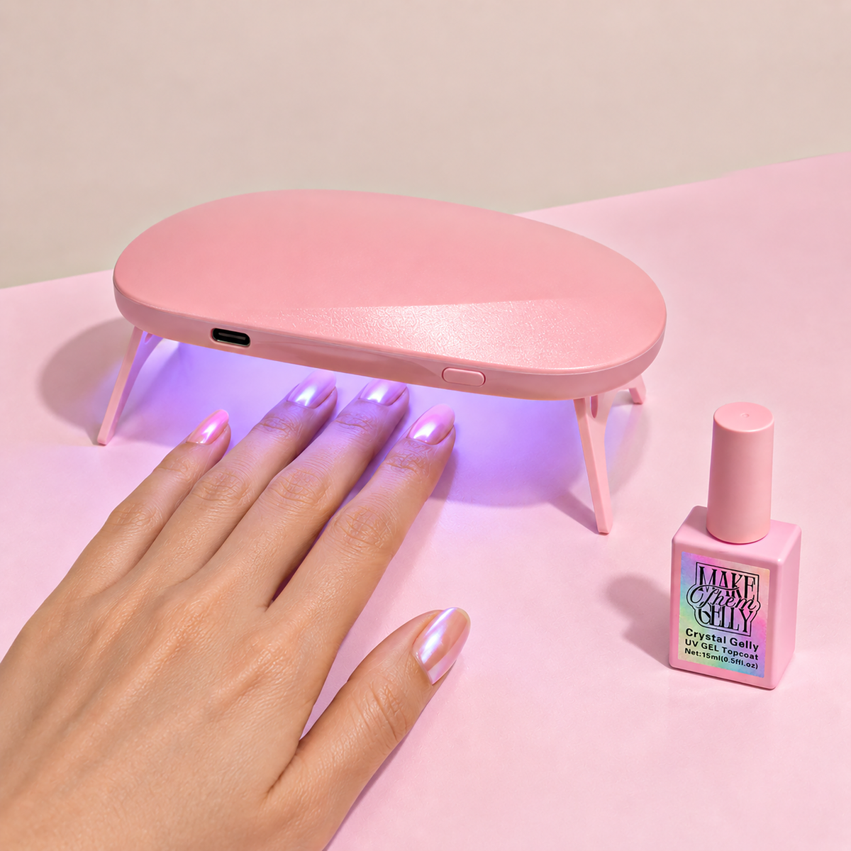 Mini Deluxe UV Gel Lamp in Pink by Make Them Gelly, worn on a hand